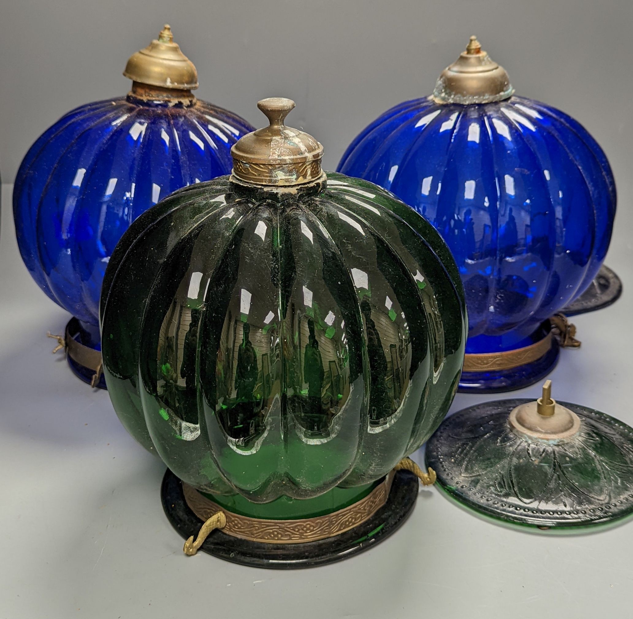 Three coloured glass pendant fluted globe shaped lamps - two blue, one green, 30 cms high.